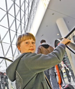 Tween boy riding escalator in shopping mall