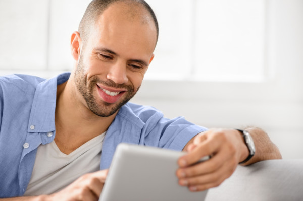 Cute guy using digital tablet at home