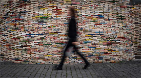 Person walking in front of a mosaic wall