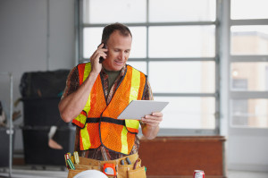 Caucasian worker talking on cell phone and using digital tablet