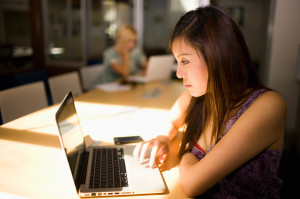 Asian businesswoman using laptop in communal workspace
