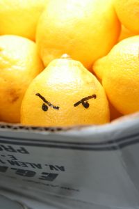 lemon with angry face in a bucket of lemons