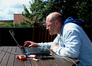 man smoking and working on laptop outside