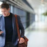 Man on smart phone - young business man in airport. Casual urban