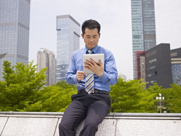 asian business executive looking at tablet computer outdoors