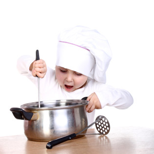 Cute happy little baby cooking something