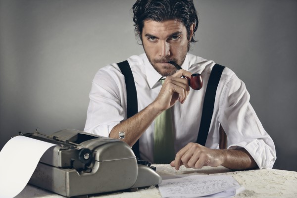 Serious copywriter smoking a pipe in front of a typewriter