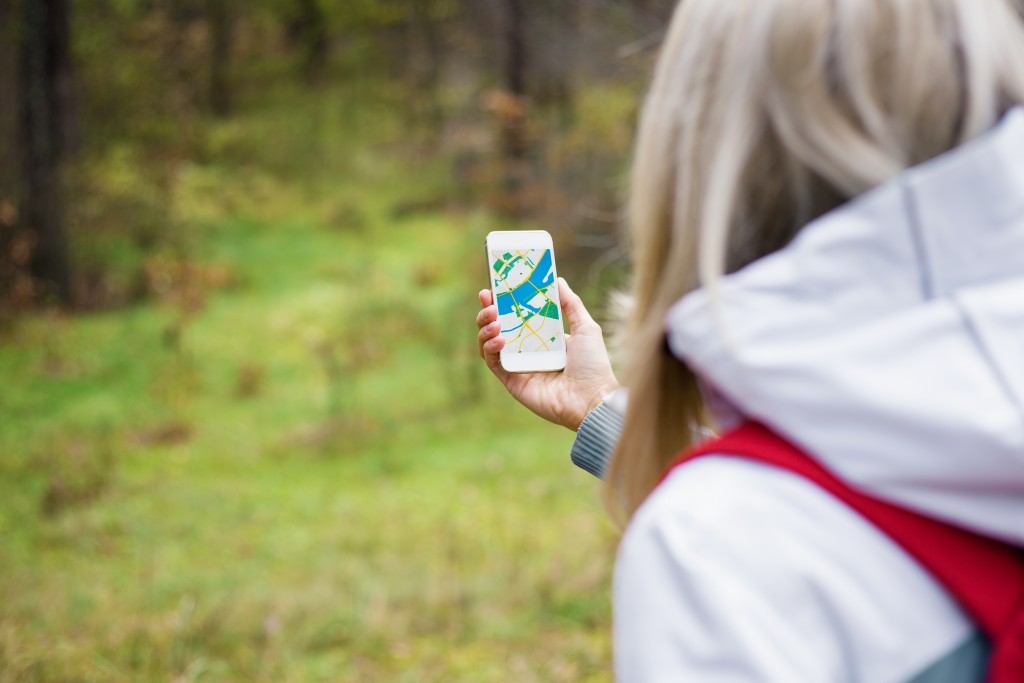 Woman geocaching in forest and using mobile app