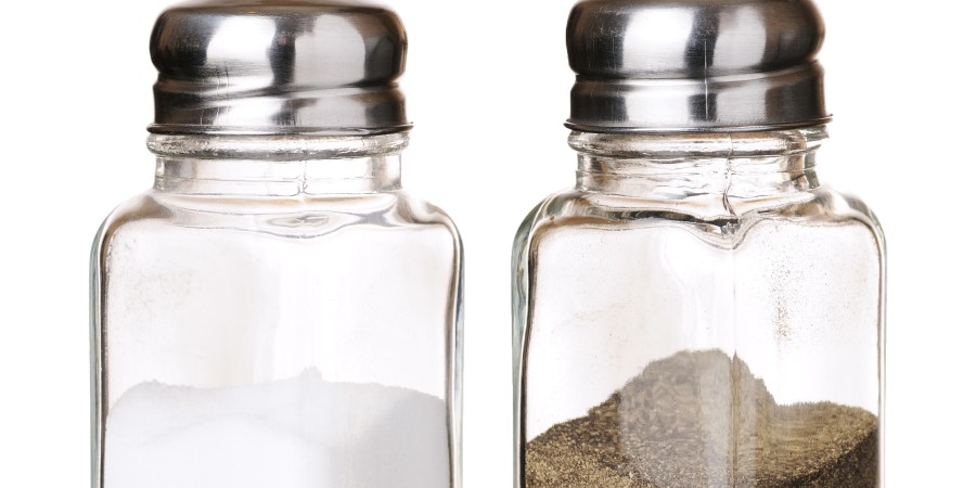 Salt and black pepper in shakers closeup isolated on white