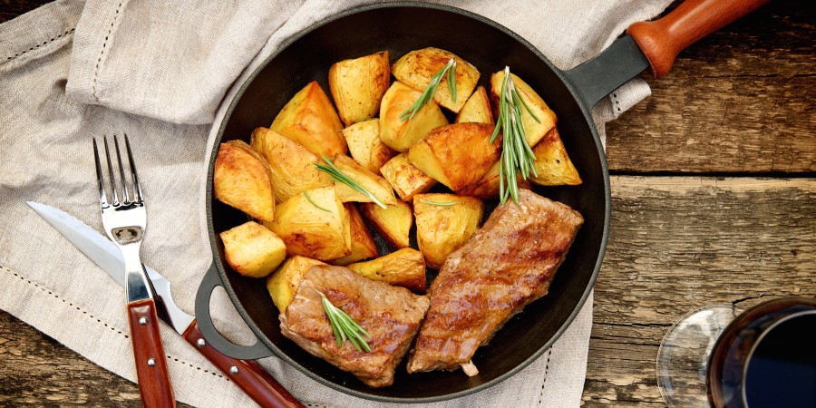 Beef steak in a pan with baked potatoes
