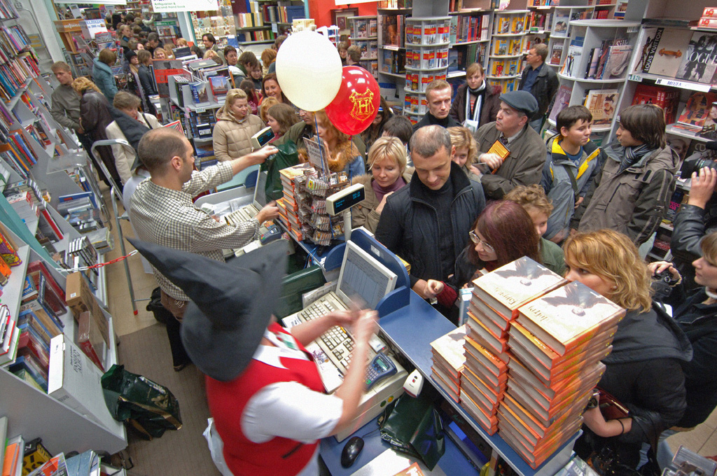 shows people lined up in a book store waiting to buy the lastest book in the Harry Potter series