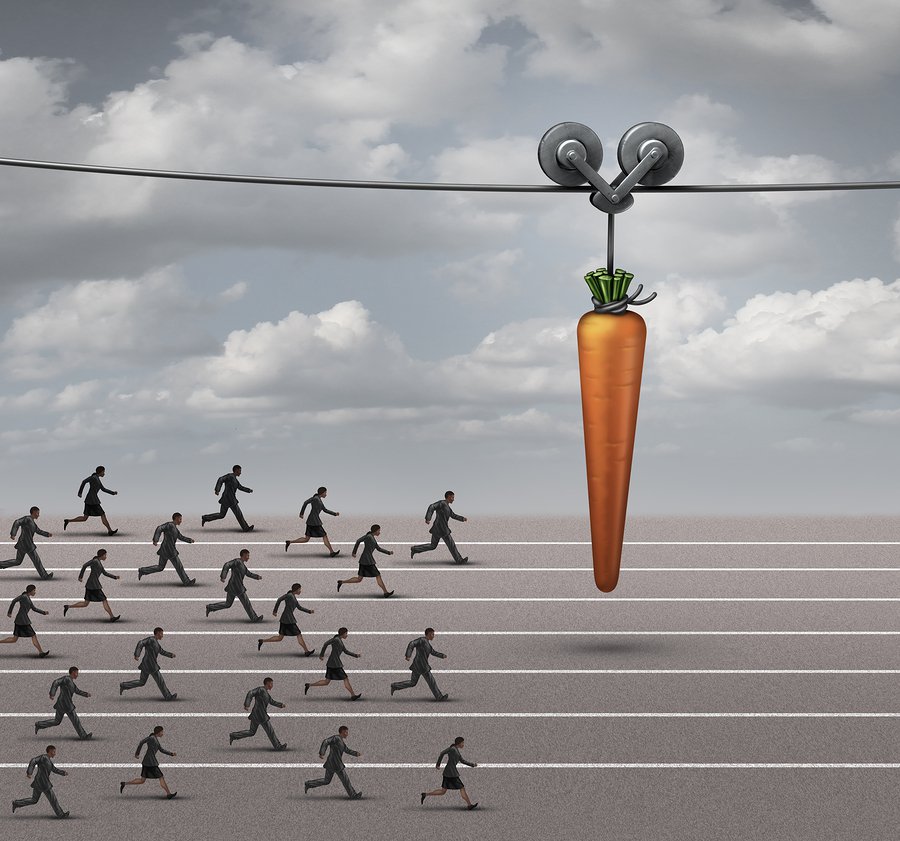 Employee incentive business concept as a group of businessmen and businesswomen running on a track towards a dangling carrot on a moving cable as a financial reward metaphor to motivate for a goal.