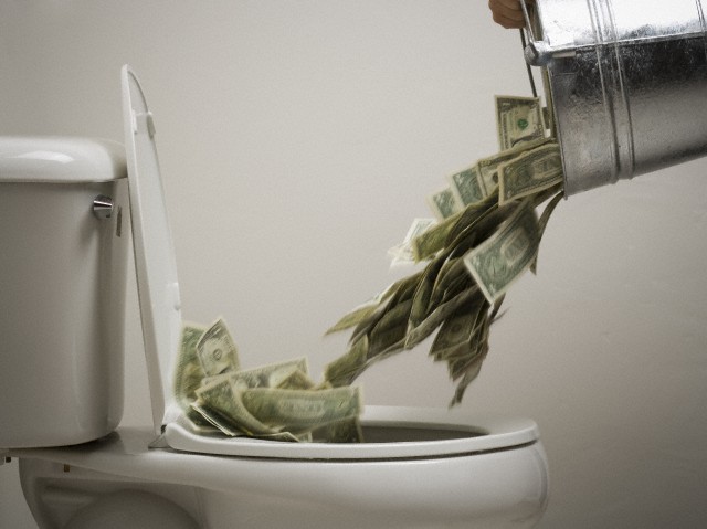 Person dumping money into a toilet bowl --- Image by © Rubberball/Corbis