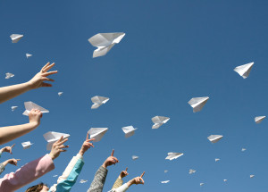 The hands of children throw upwards messages in the manner of paper airplanes.