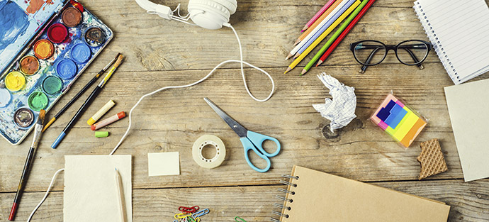 Desk of an artist with lots of stationery objects. Studio shot on wooden background.