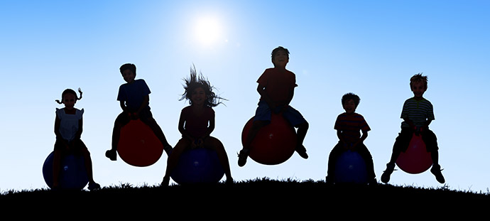 Silhouettes of Children Playing on Balls and Copy Space Above
