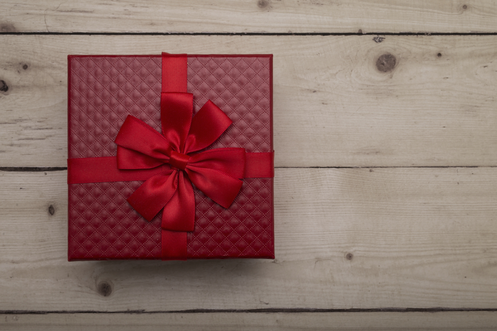 Top view of luxurious red colored present box over wooden background