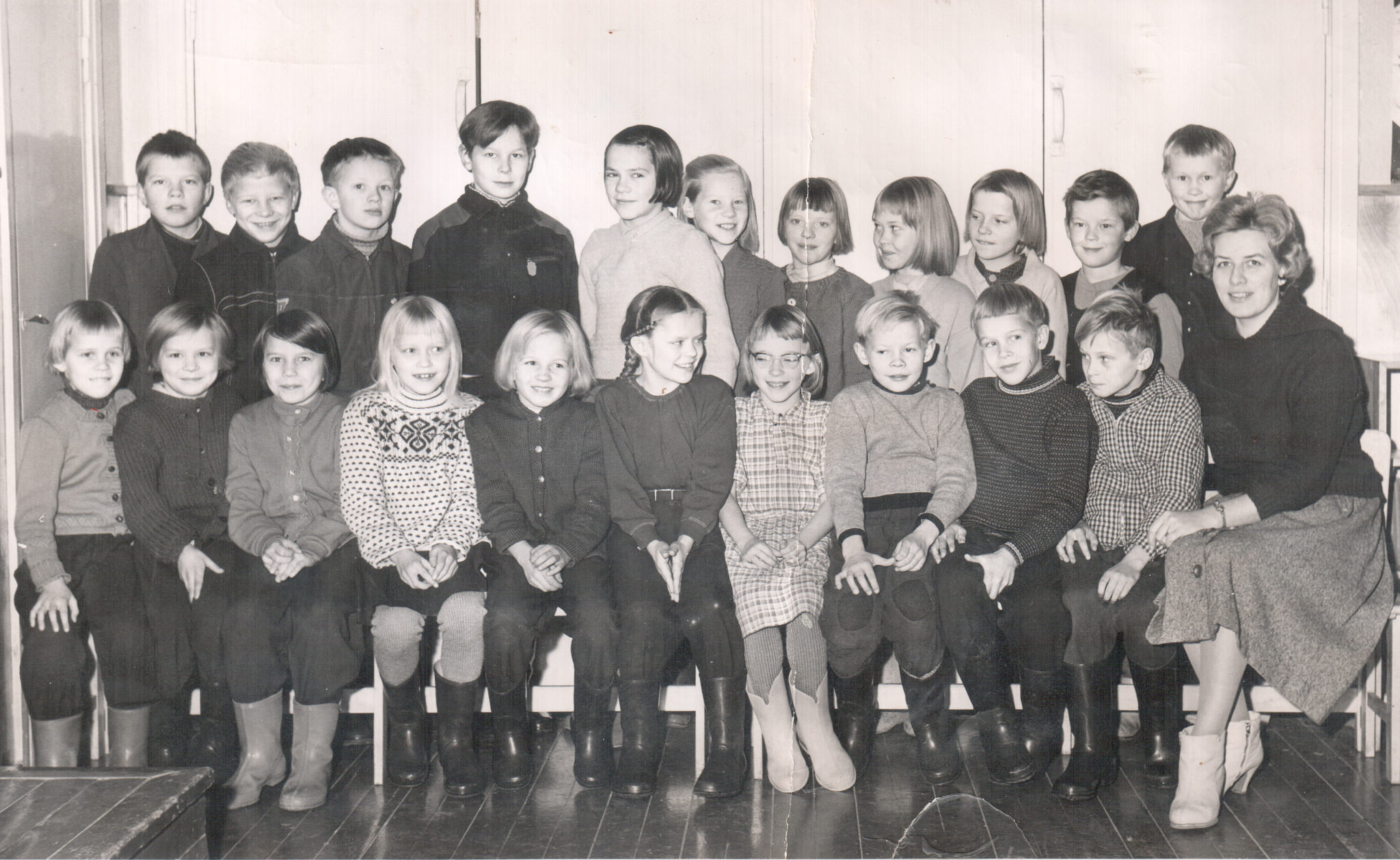 black and white school photo of  children sitting with their teacher