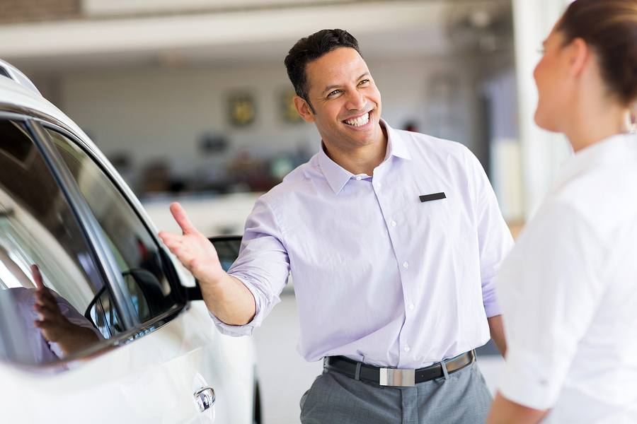 friendly salesman selling car to a customer in showroom