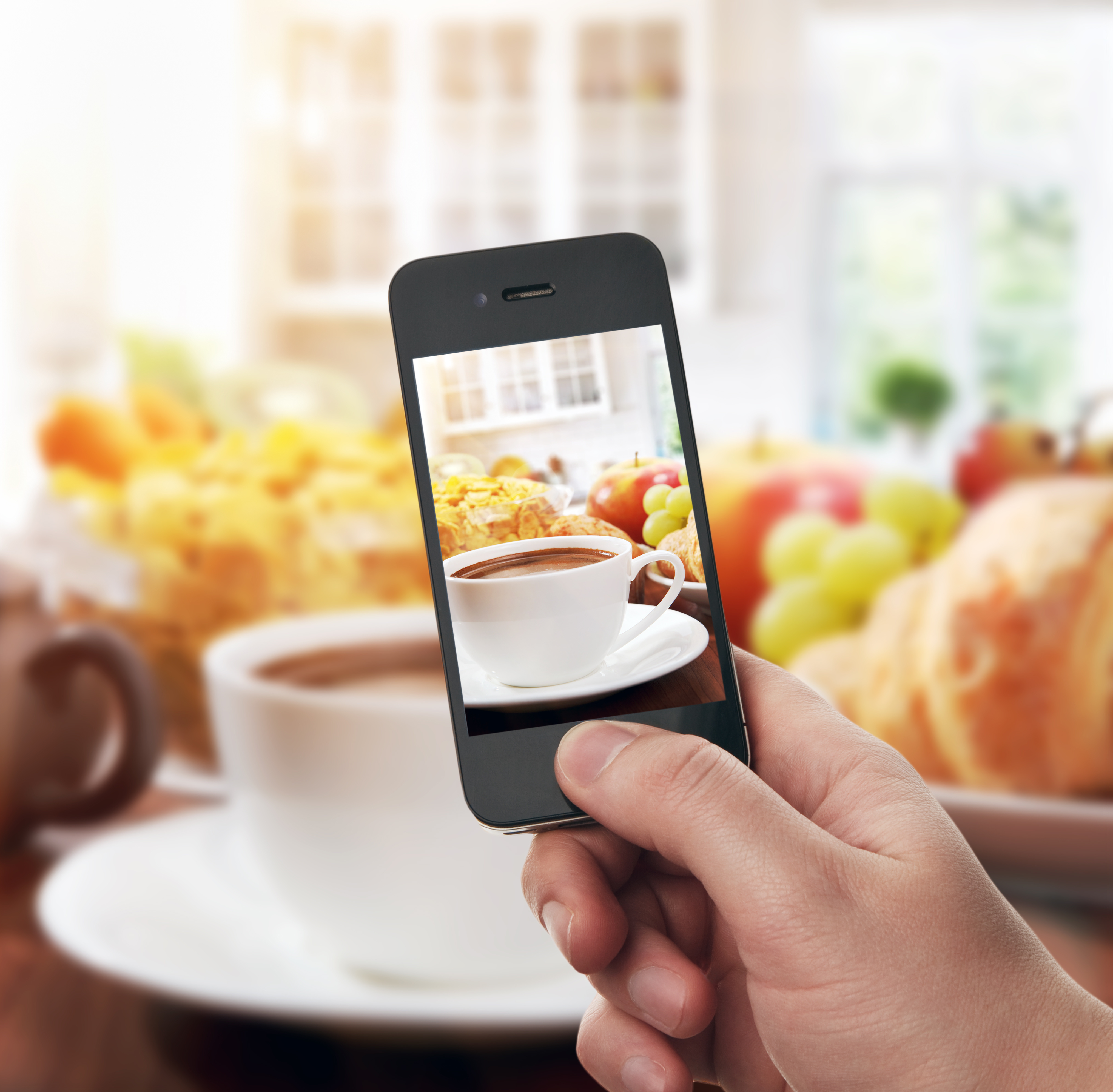 Hand with smartphone taking food photo of fresh healthy breakfast with cup of coffee