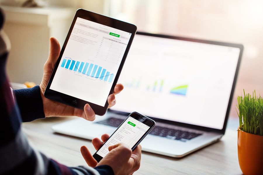 A man hand holding screen Apple app showing on IPad mini and Iphone 6 in office. Apple is the most valuable technology company in the World. PRAGUE, CZECH REPUBLIC - NOVEMBER 17,2015