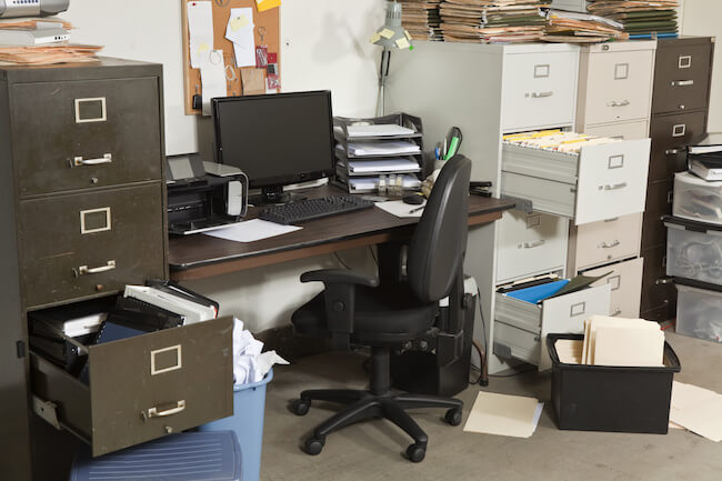 Very messy office with piles of files.