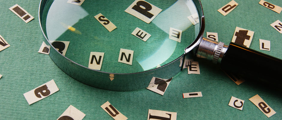 An assortment of letters and typefaces being examined by a magnifying glass