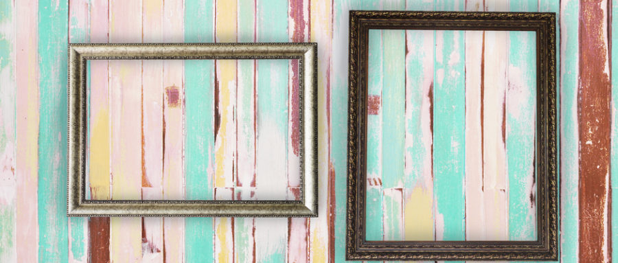 two empty rectangular picture frames hanging on a pastel striped painted wall