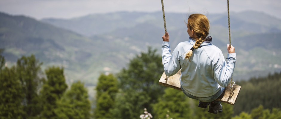 woman on swing looking towards mountains