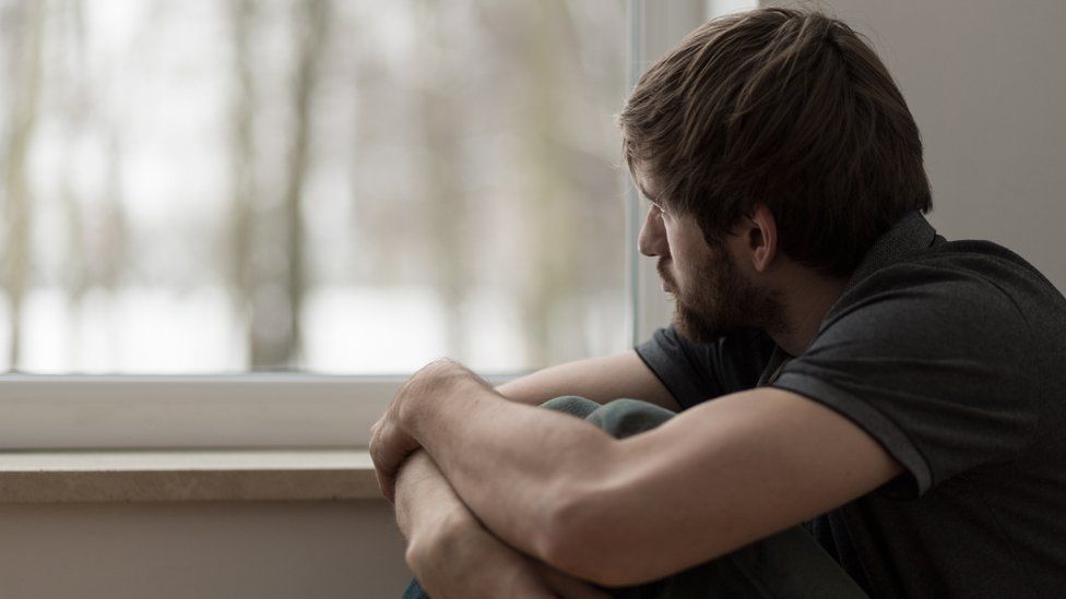 Working remotely lonely man sitting by window