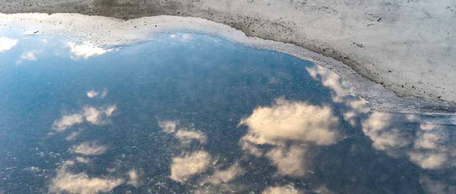 a puddle with a cloud reflection