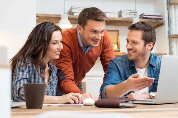 Business people smiling together while looking at laptop in office