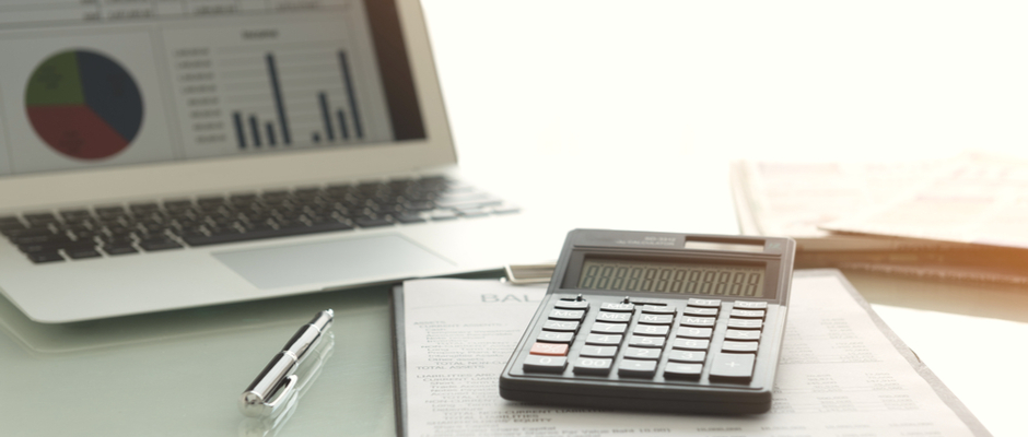 a calculator and a computer with accounting software on screen