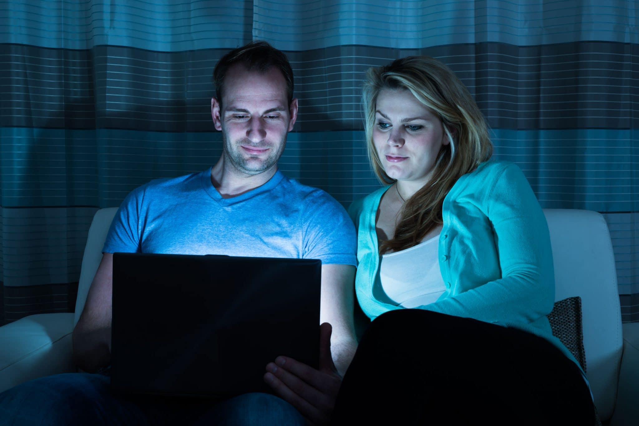 Happy couple watching movie on laptop at home