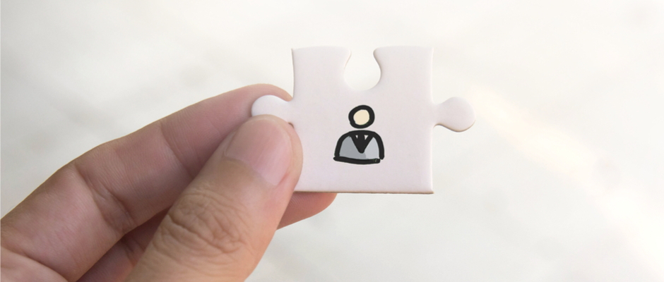 a finger and thumb holding up a puzzle piece with a person on the puzzle piece
