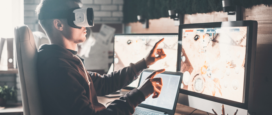 virtual reality developer with headset on looking at three screens