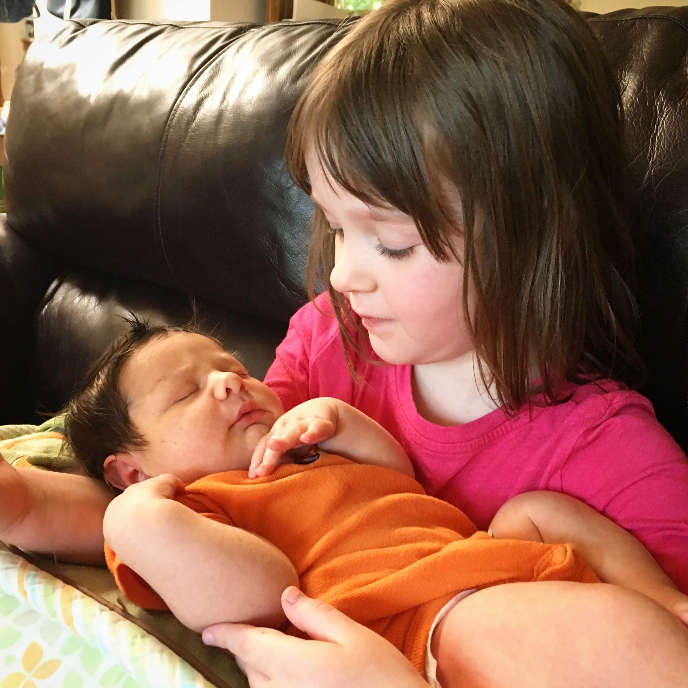 A picture of a little girl holding her baby brother.