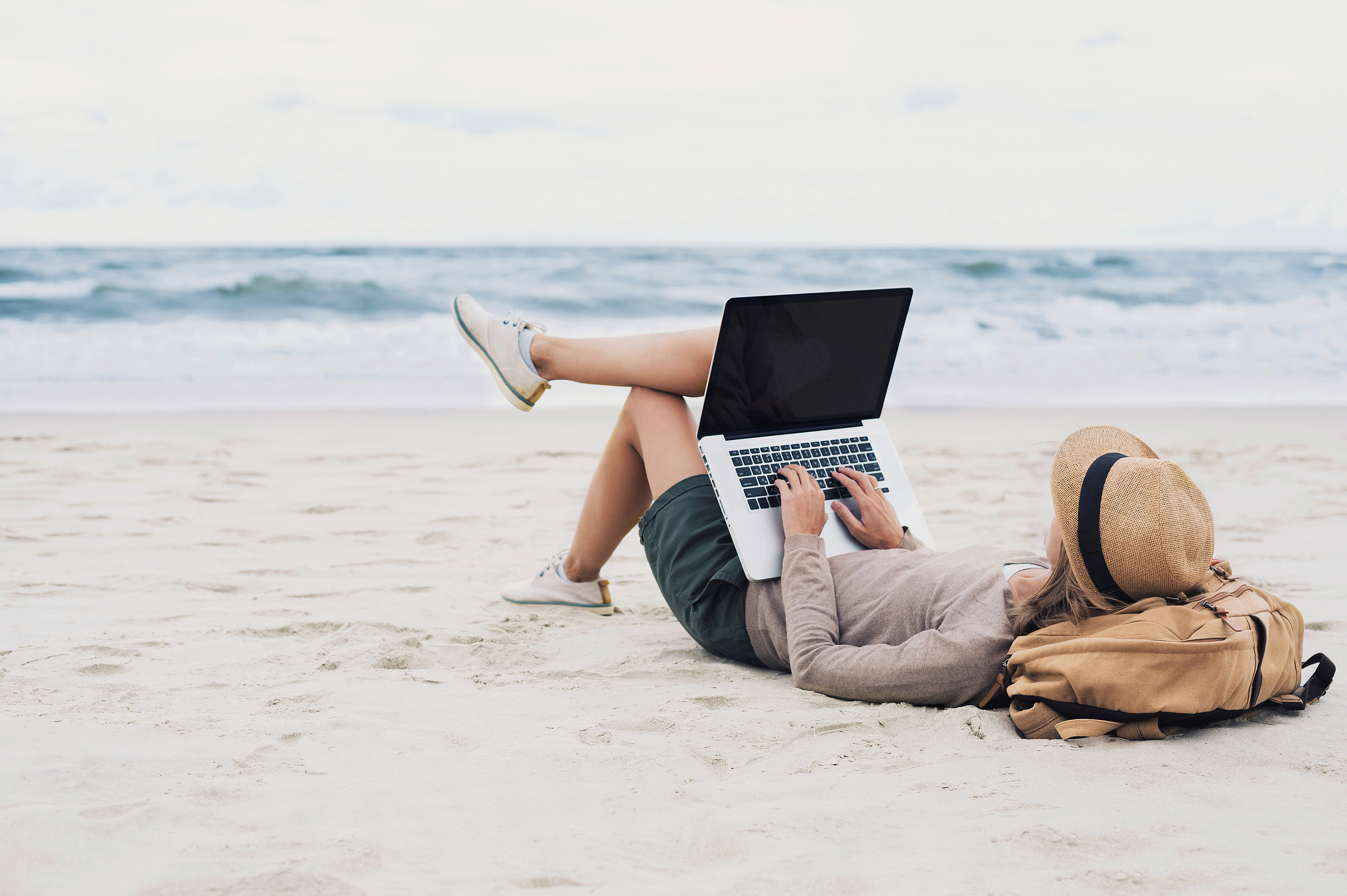 freelancer working while laying down on a beach