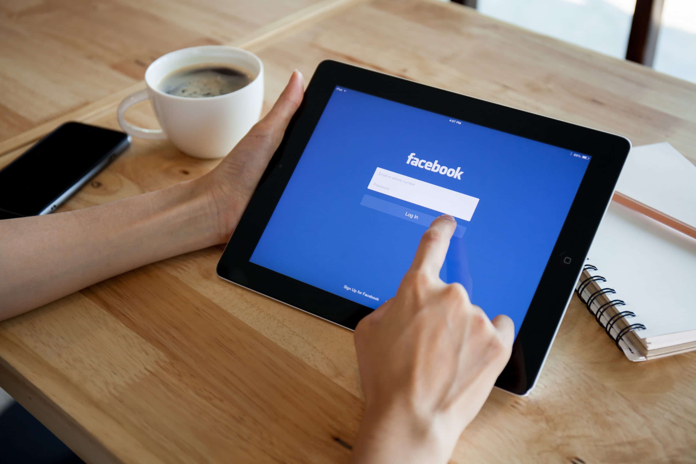 Person looking at tablet with Facebook logo