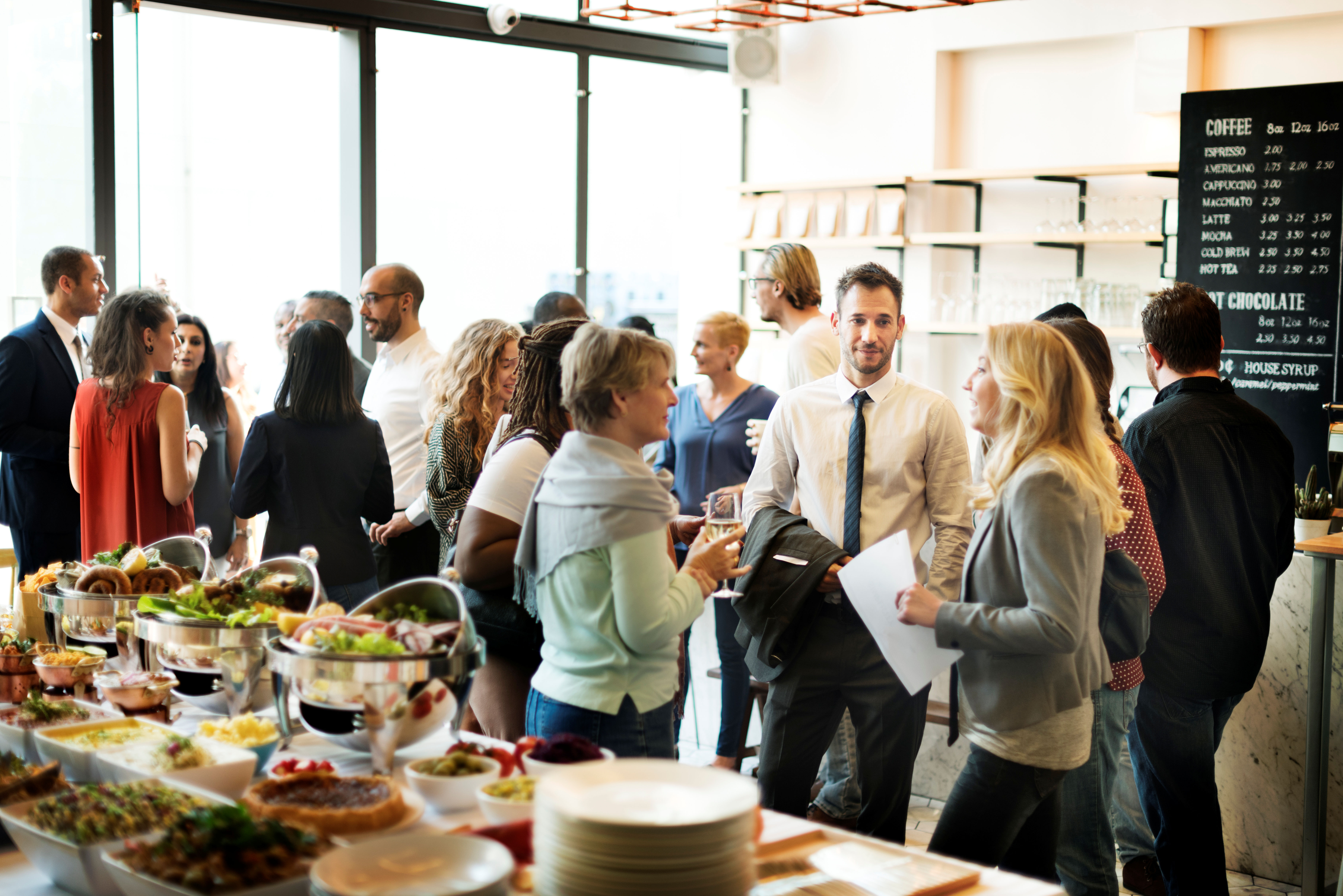 A group of men and women at a business event at a coffee shop.