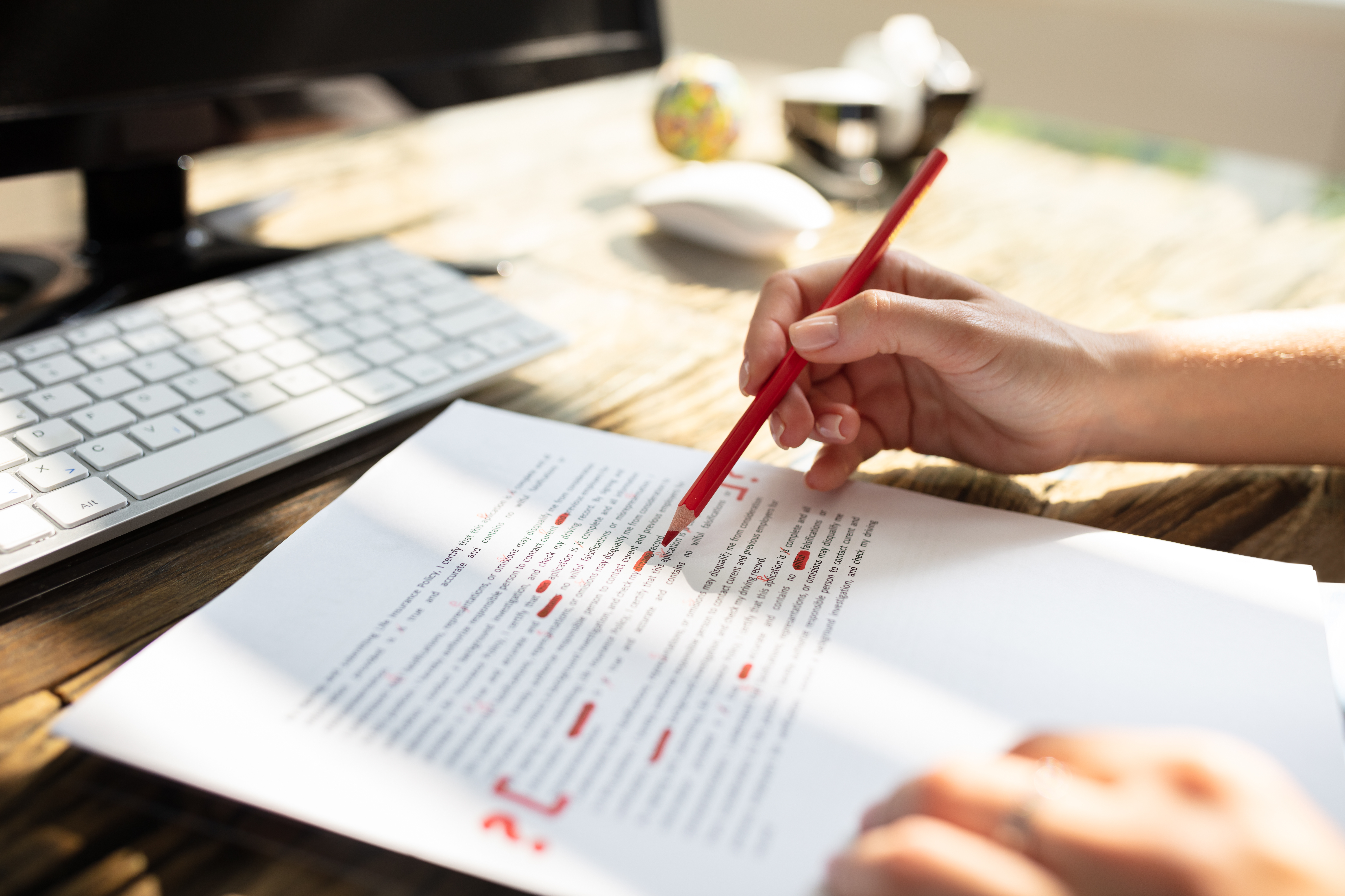 Close-up Of A Persons Hand Marking Error With Red Marker On Document