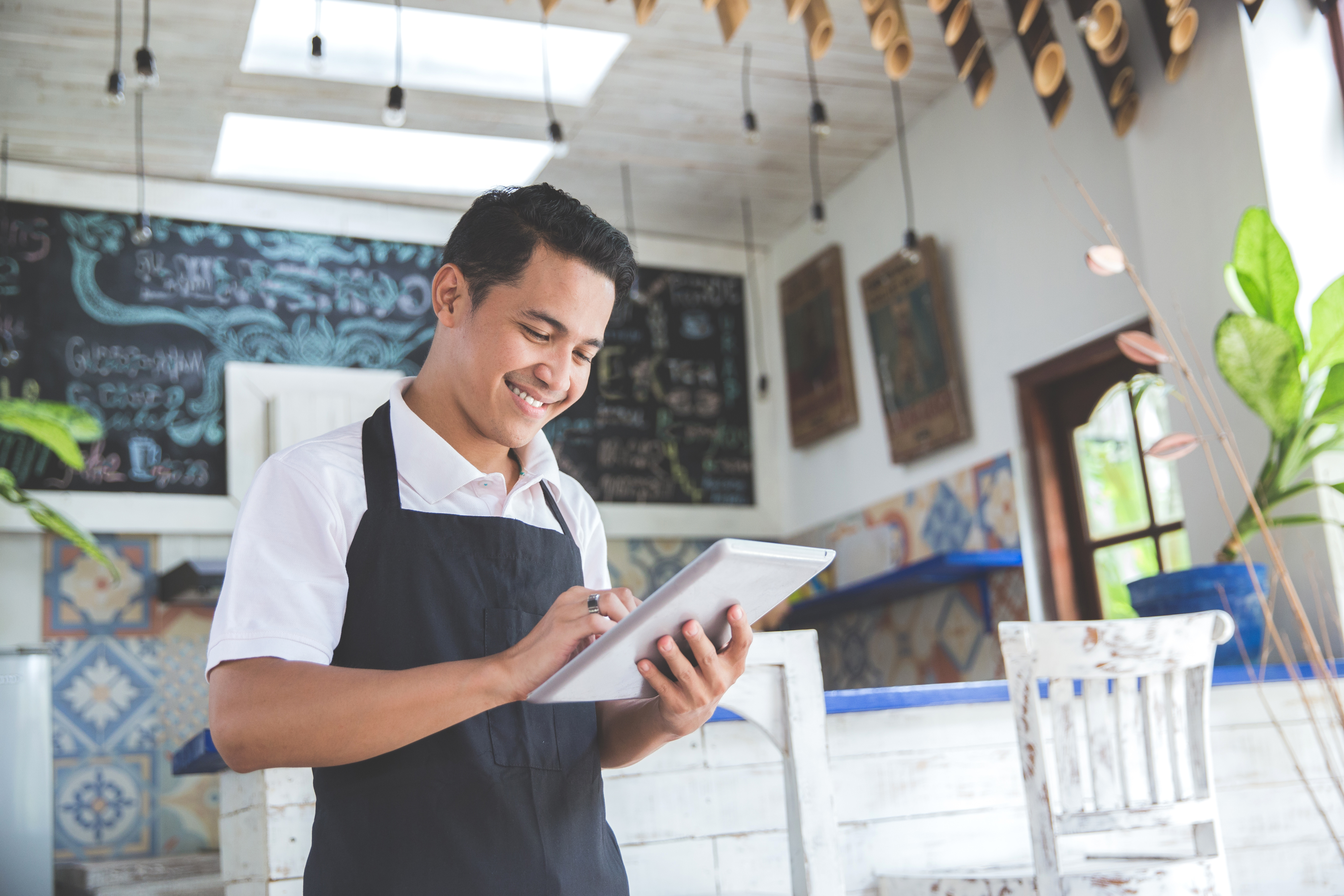 Online Presence - portrait of Asian young male cafe owner with tablet