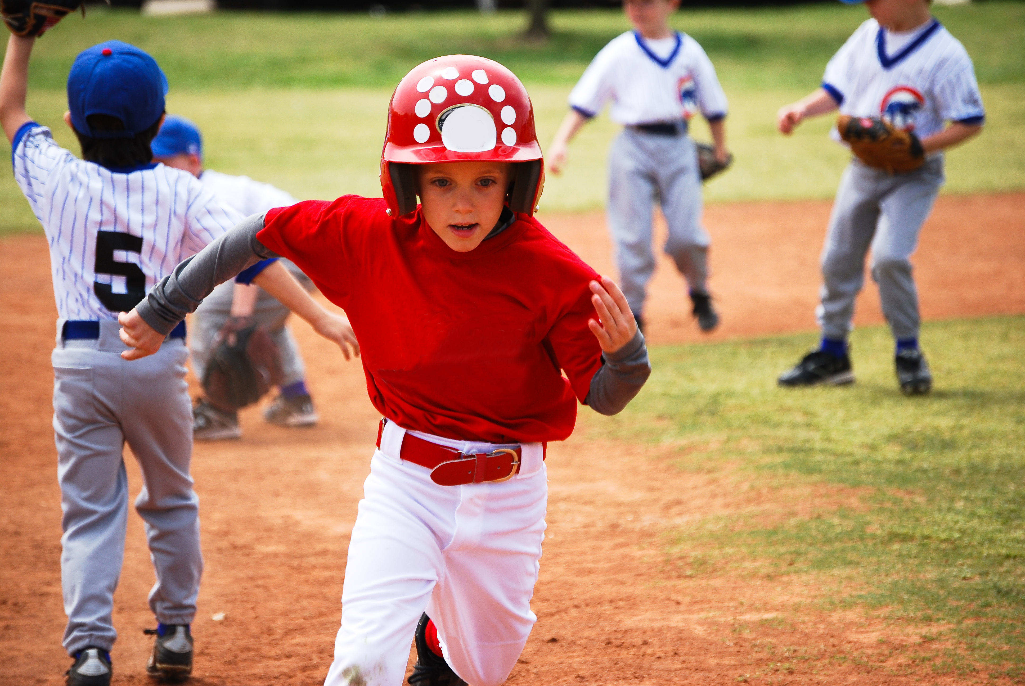little league baseball player rounding 3rd base.