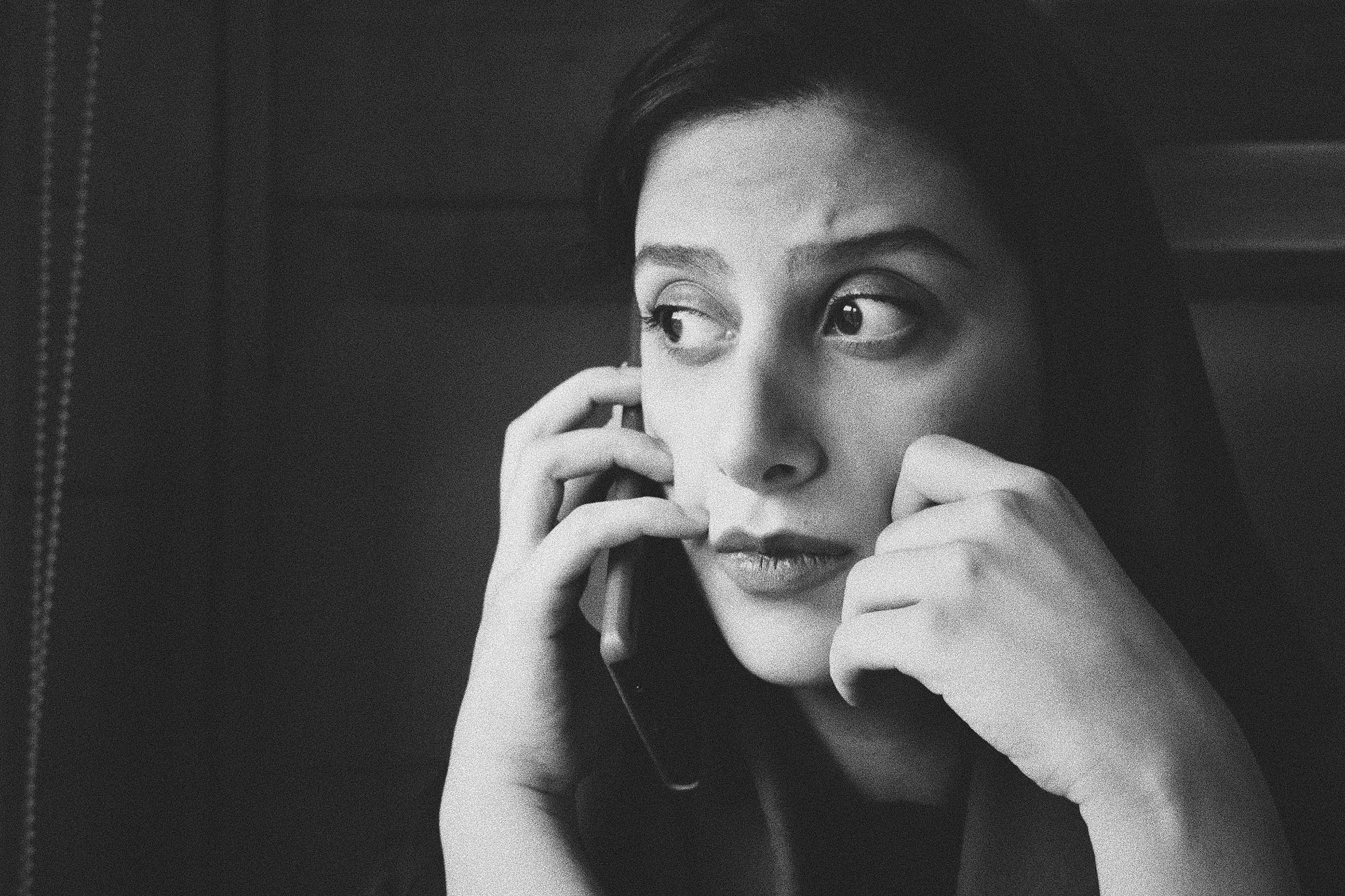 black and white image of woman looking anxious on mobile phone