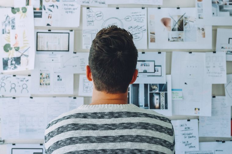 back of a person's head looking at a wall with papers on it