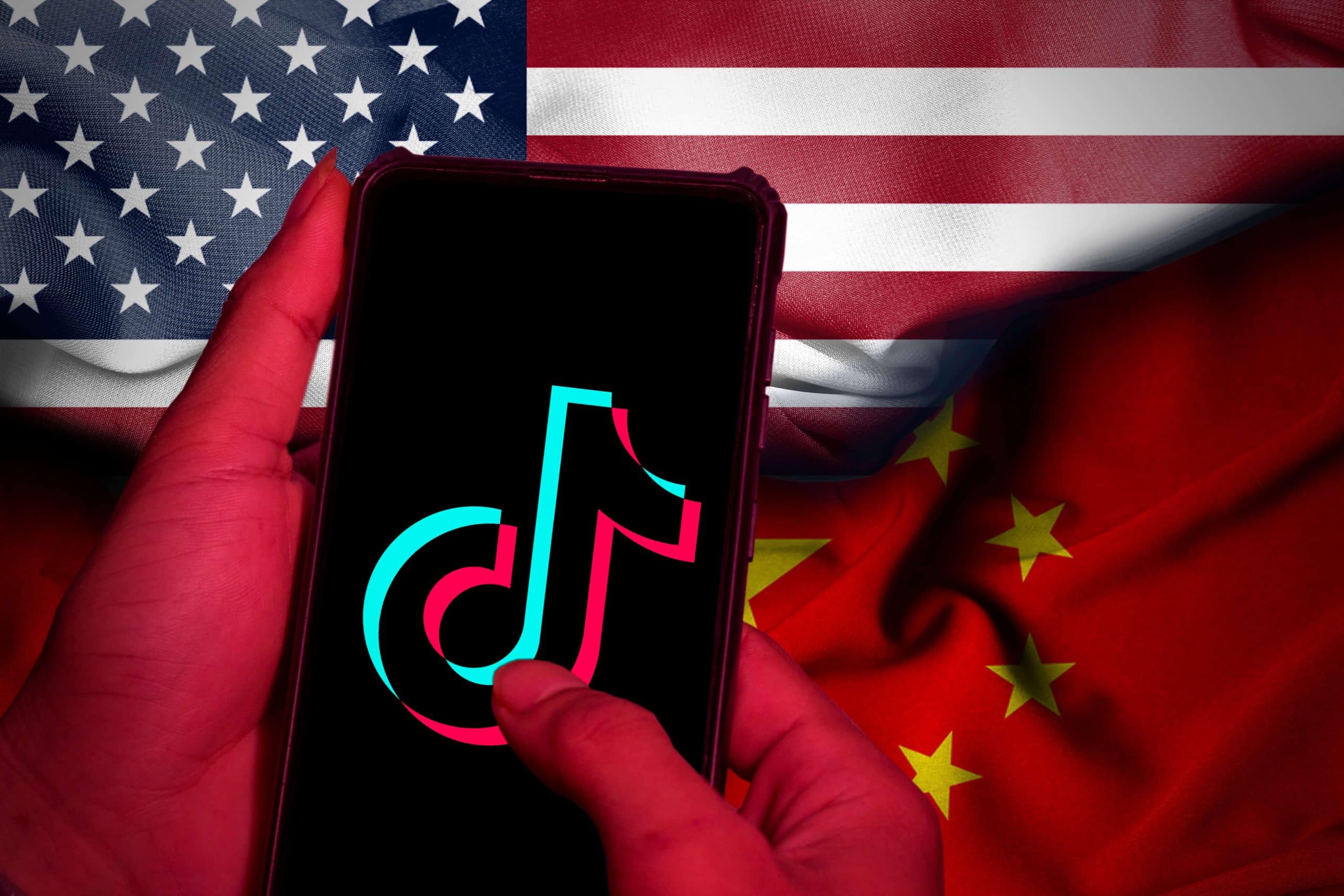 phone with a TikTok logo in front of a us flag and china flag