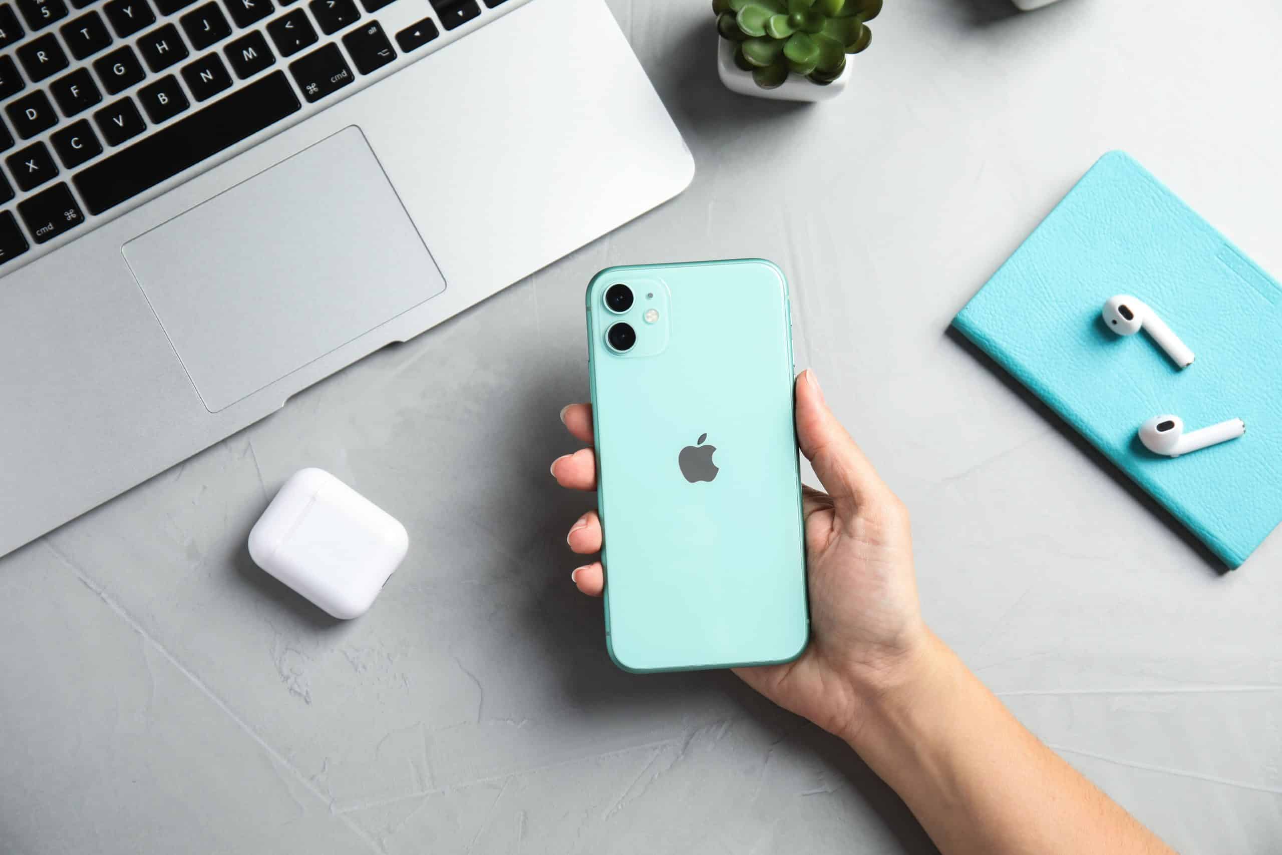 Woman holding Iphone 11 green at table, top view