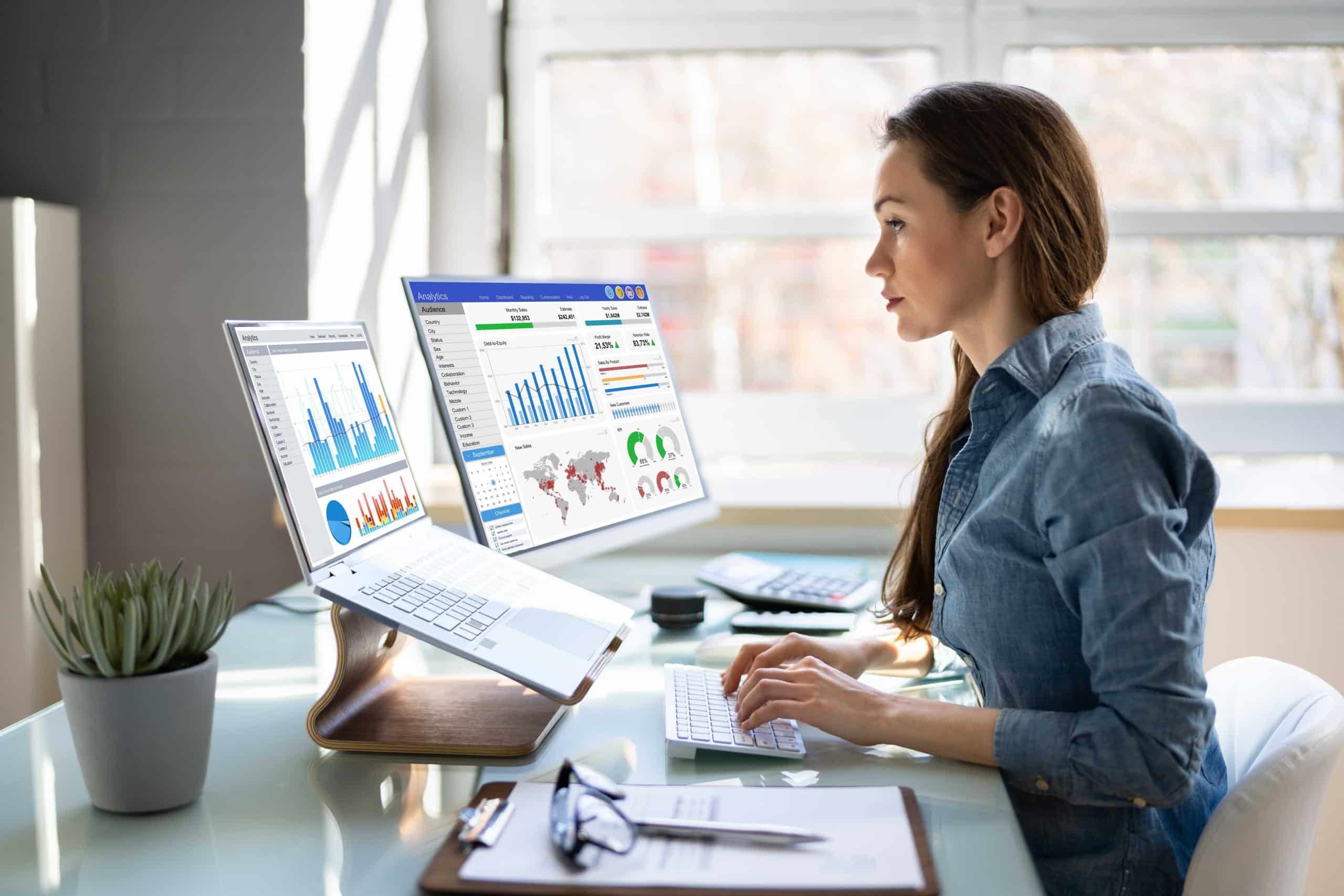 woman at a computer with multiple monitors looking at analytics