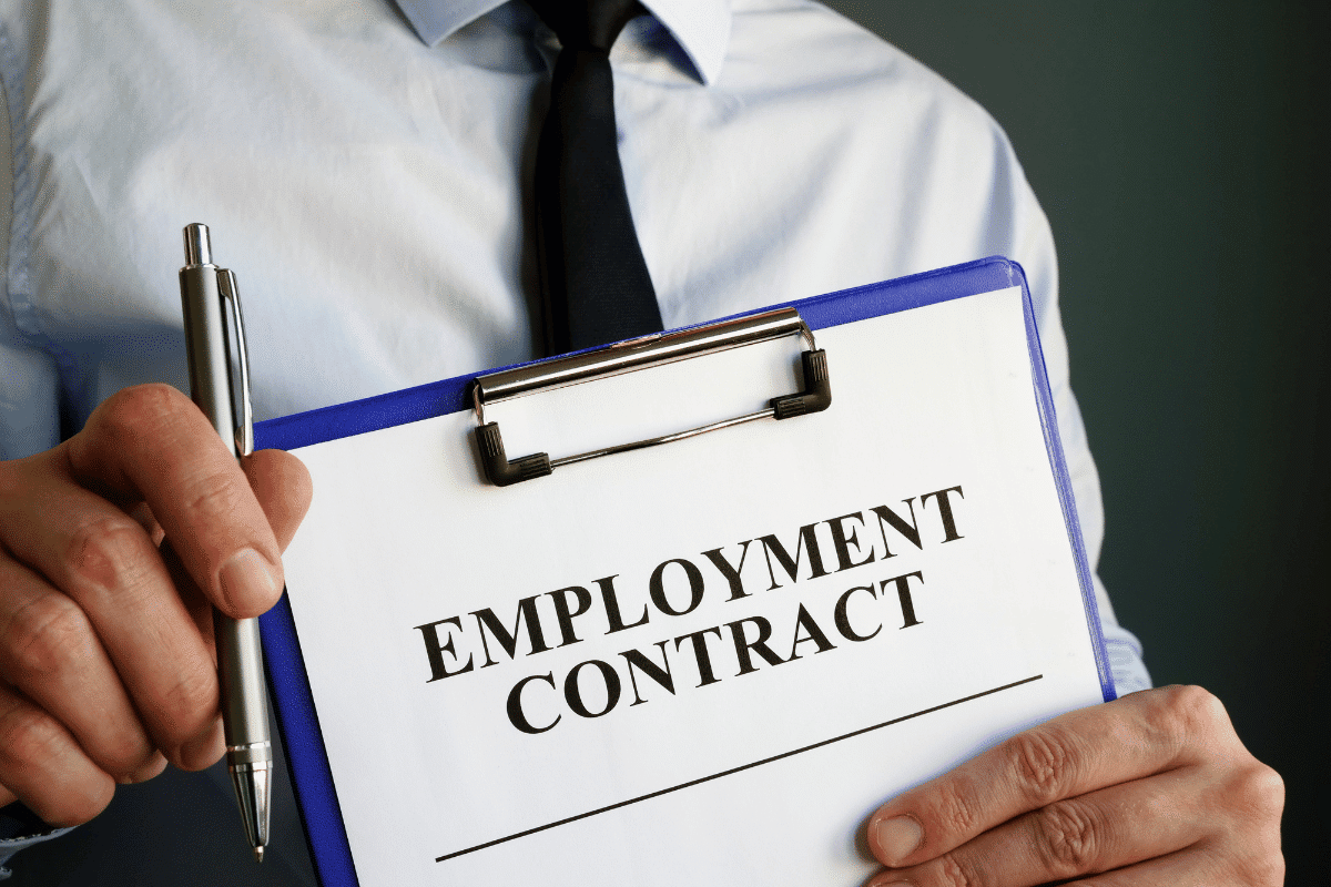 Business professional holding employment contract clipboard and pen close up human resources hiring agreement document concept. Oklahoma small employer incentive bill changes explained