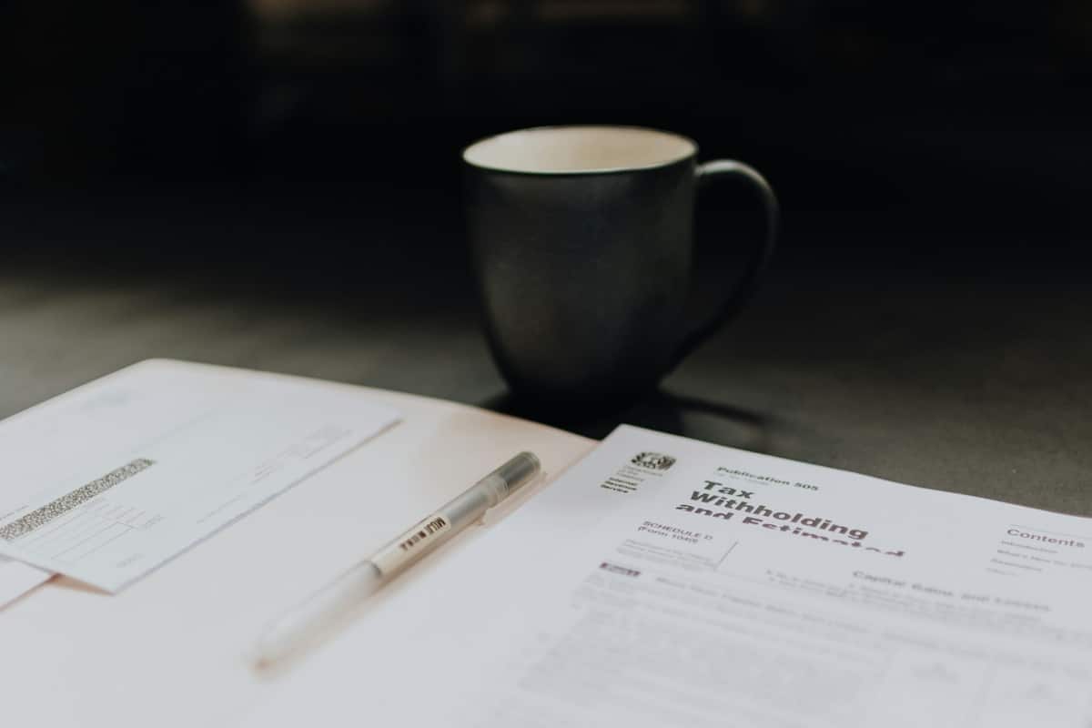 Photograph of a tax withholding form on a desk with a cup of coffee and other paperwork.